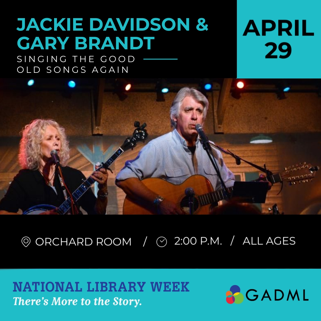 Jackie Davidson playing banjo and Gary Brandt playing guitar. Both are singing.
